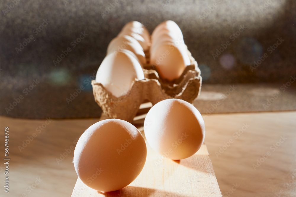 White chicken eggs in cardboard on wooden surface with interesting light. The concept of taking pictures of food. Fresh eggs from the farm. Organic egg production. Chicken egg industry. Eggs for sale. White chicken eggs in cardboard on wooden surface with interesting light. The concept of taking pictures of food. Fresh eggs from the farm. Organic egg production. Chicken egg industry. Eggs for sale.
