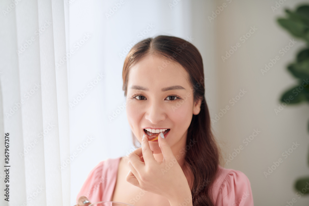 Young beautiful Asian woman eating pill and drinking water Young beautiful Asian woman eating pill and drinking water