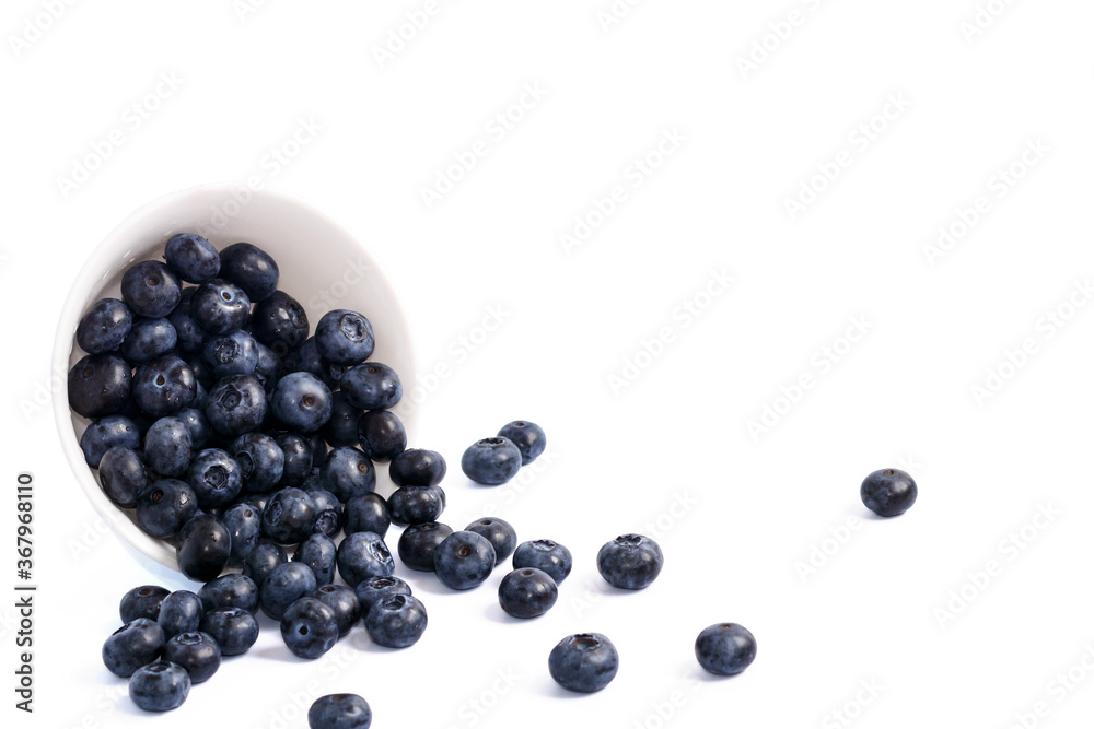 Blueberries in a white ceramic bowl spilled out. On a white background, isolated on white. Blueberries in a white ceramic bowl spilled out. On a white background, isolated on white.