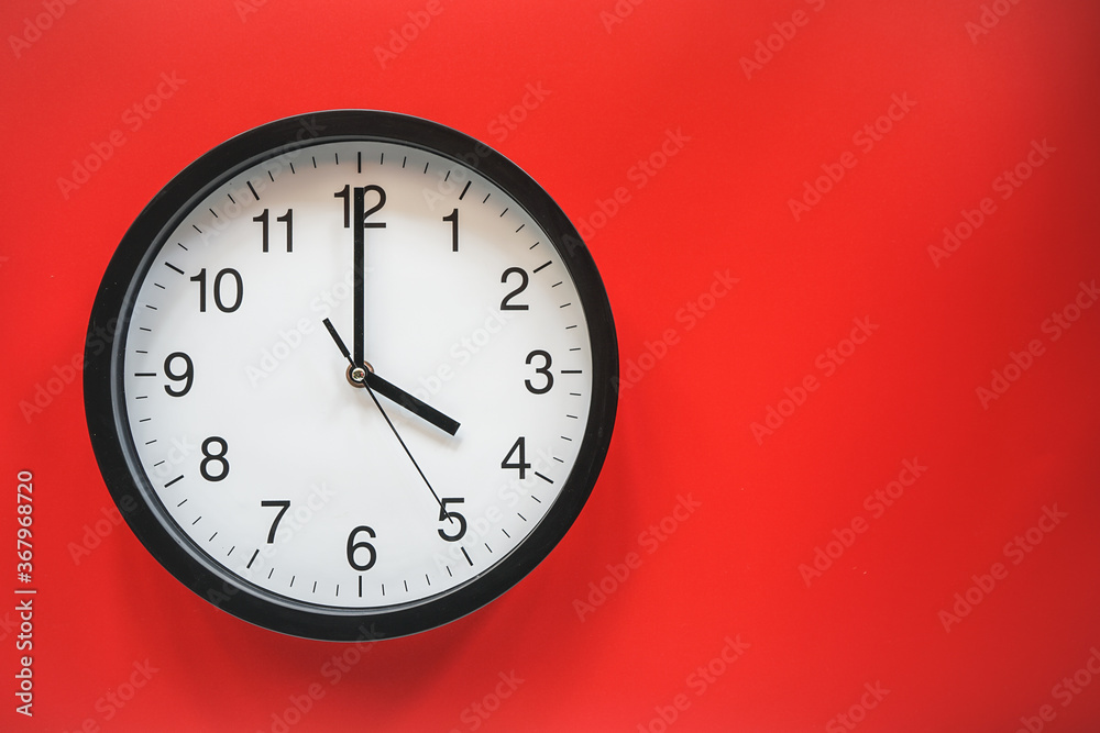 Classic black and white analog clock on red background at Four o'clock with copy space Classic black and white analog clock on red background at Four o'clock with copy space
