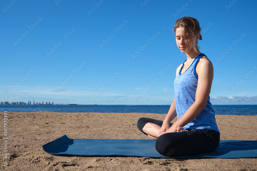 Young slender girl doing yoga on the beach on a sunny morning, sad mood, sad thoughts Young slender girl doing yoga on the beach on a sunny morning, sad mood, sad thoughts