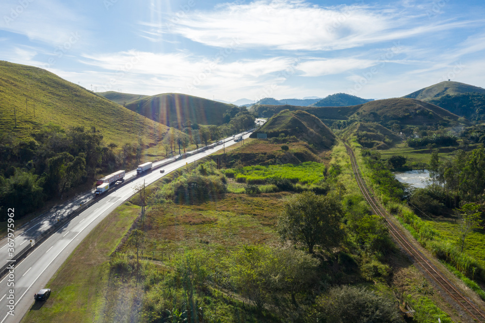 Highway with river and train road. Aerial landscape view of a scenic road in the valley surrounded by the beautiful Brazilian Mountains. 