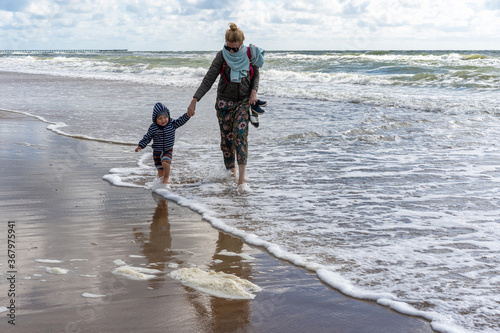 Young woman and little boy having fun running and playing across sandy windy Baltic sea beach..Vacation and lifestyle concept..