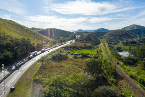 Highway with river and train road. Aerial landscape view of a scenic road in the valley surrounded by the beautiful Brazilian Mountains. 