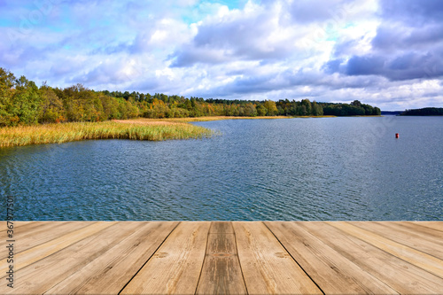 Wooden platform over the autumn lake. Empty wooden jetty on the lake shore. 
