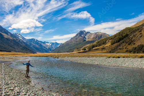 A fly fisherman casting for trout on the Ahuriri River in New Zealand photo