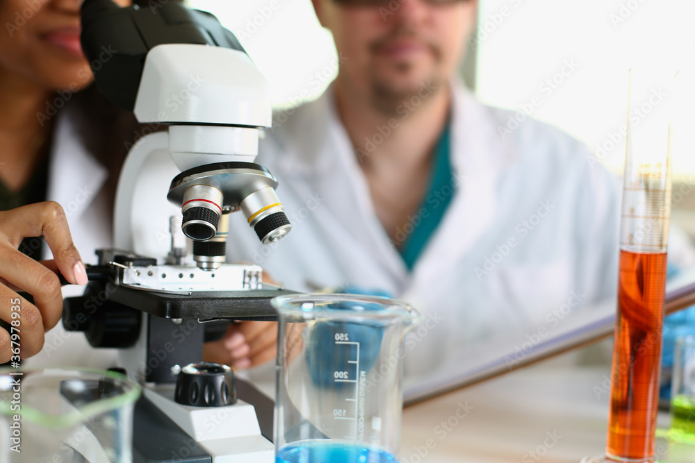 Two scientists of a student chemist are conducting research using microscope for bacterial contamination of water to search for vaccine to treat diseases in medicine Two scientists of a student chemist are conducting research using microscope for bacterial contamination of water to search for vaccine to treat diseases in medicine