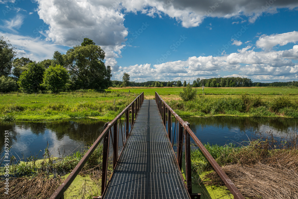 View on the steel footbridge on the Liwiec river at sunny day near Mokobody, Masovia, Poland