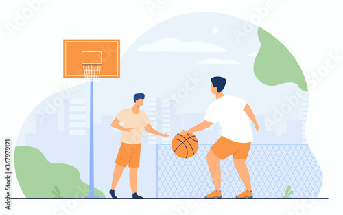 Sport games outdoors concept. Two athletic young men playing basketball in urban stadium. Guys training on outdoor court with fence in background. Can be used for match, sport activity concepts