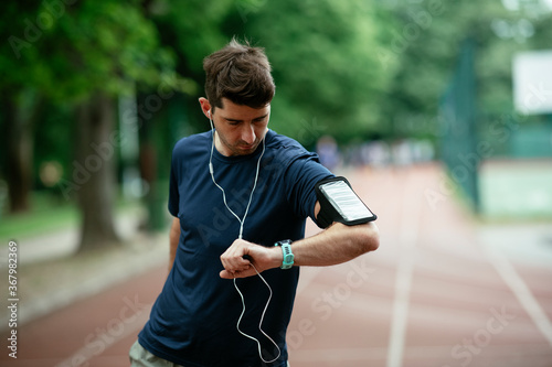 Young man checking his heart rate during work out. Young man exercising on the athletics track