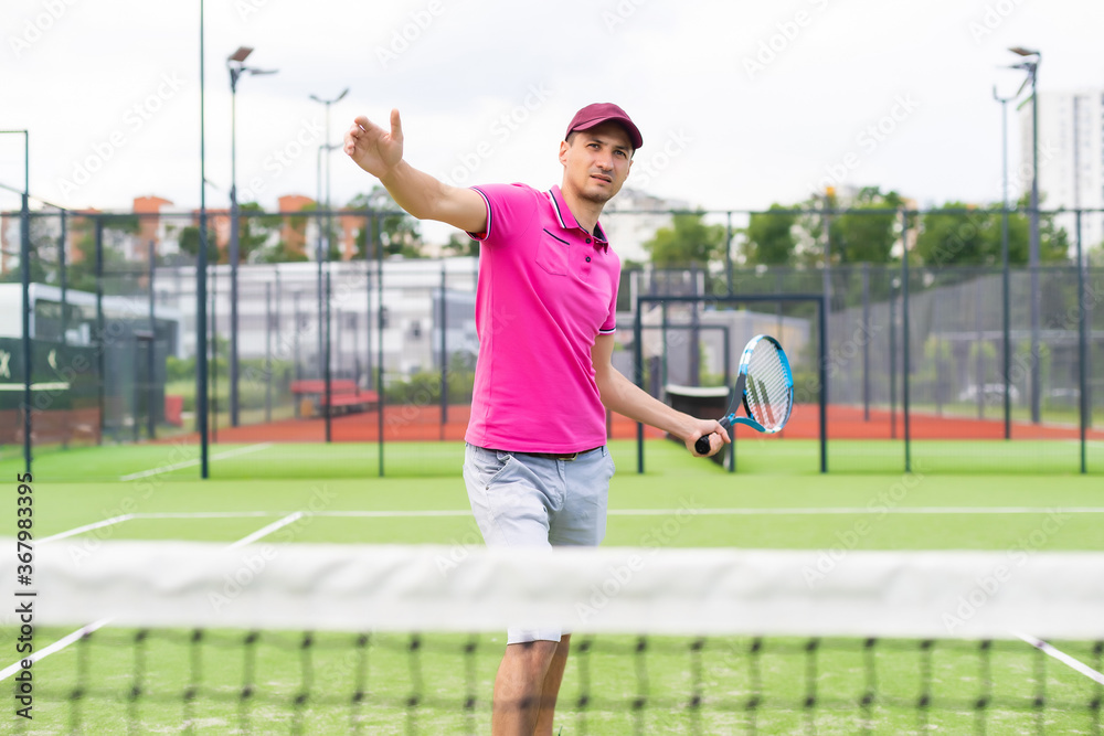 Male tennis player at the court looking happy