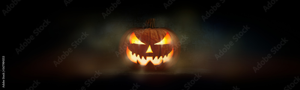 One spooky evil halloween lantern, Jack O Lantern, with glowing eyes and face on a dark background.