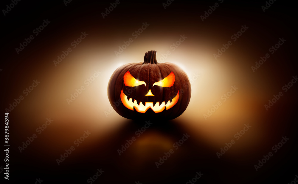 A back lit halloween lantern, Jack o Lantern, with a spooky evil face with glowing eyes against a dark background. - obrazy, fototapety, plakaty 