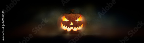 Obraz na płótnie One spooky evil halloween lantern, Jack O Lantern, with glowing eyes and face on a dark background. w salonie