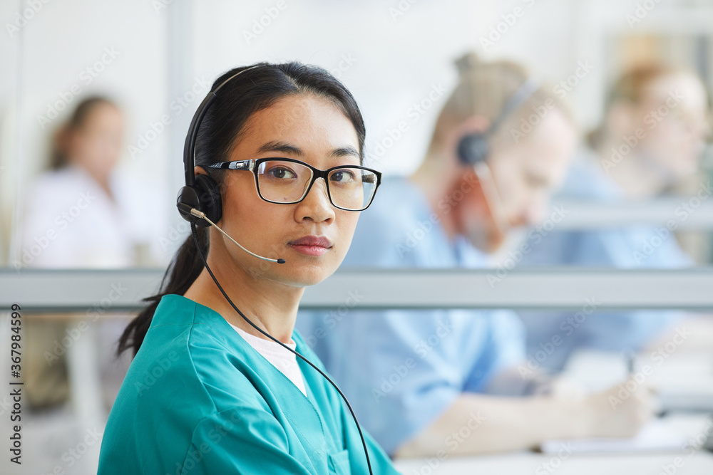 Portrait of Asian medical customer service operator in headset looking at camera during her work Portrait of Asian medical customer service operator in headset looking at camera during her work