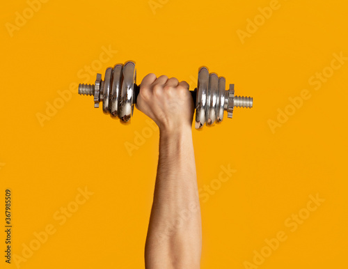 Canvastavla Male hand lifting heavy dumbbell on orange background, closeup