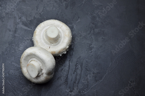 Raw champignon mushrooms on dark background. Vegan food concept.