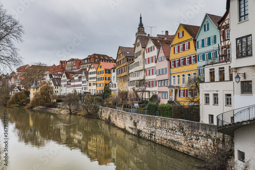 Historical houses reflect on the River Neckar  s water with Saint George Church bell tower above the typical pitched roofs. Medieval architecture glimpse at the popular Neckarfront - Tubingen  Germany