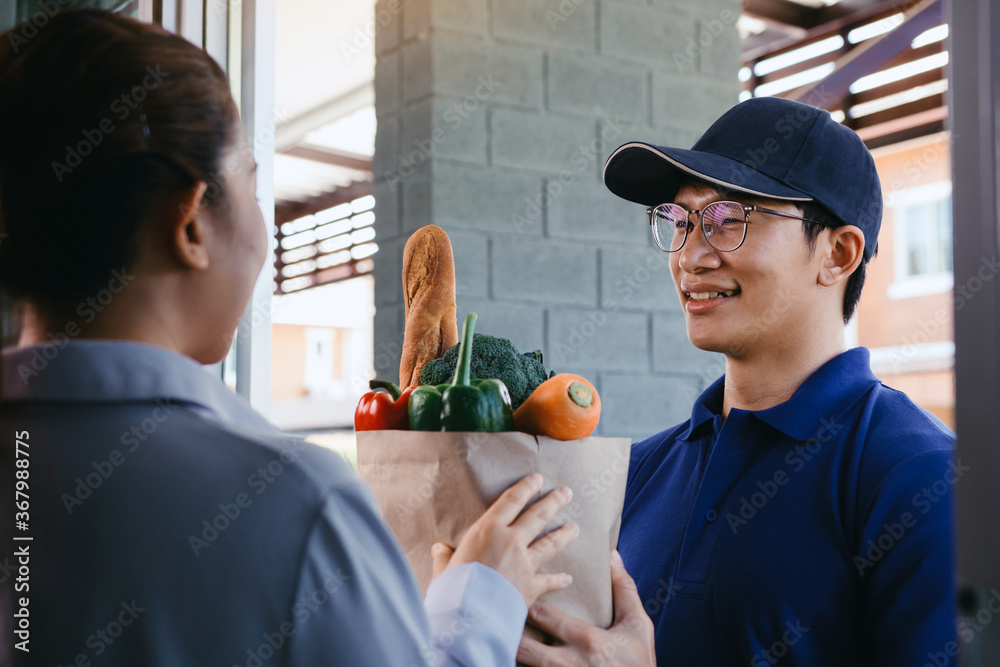 Delivery of an asian man handling a bag of food to a female customer at the door. Delivery of an asian man handling a bag of food to a female customer at the door.