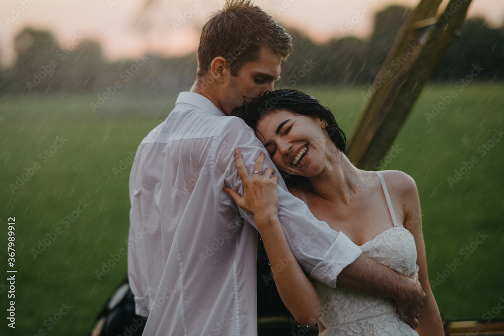 Happy couple in love embraces under drops of rain.