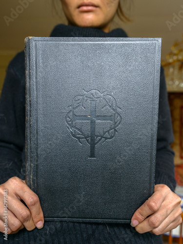 Portrait of young beautiful Asian woman holding bible at home