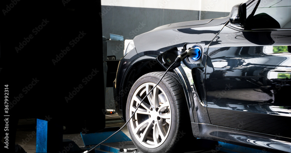 Fototapeta premium Power supply connect to electric car for add charge to the battery. Charging re technology industry transport which are the future of the Automobile with city background.