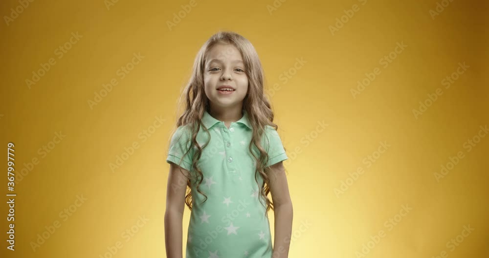 Little caucasian girl looking at camera and bursting into laughter, expressing positive emotions, isolated on yellow background - emotions concept close up 4k Little caucasian girl looking at camera and bursting into laughter, expressing positive emotions, isolated on yellow background - emotions concept close up 4k