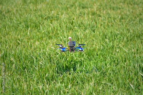 Racing drone flying over green field