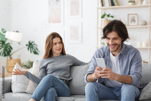 Angry woman looking at her boyfriend chatting with girl