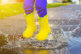 My rubber-booted feet are Bouncing in a puddle. Article about rubber boots. Children's summer shoes. Puddles after rain. Bad weather. A child jumps in a puddle. Happy childhood. A happy boy in rubber 