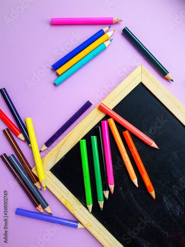 Chalkboard, colored pencils on a purple background. Back to school.