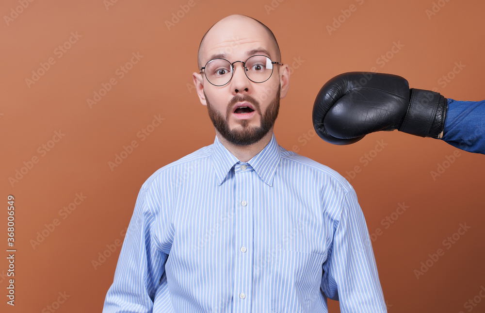 Naklejka premium A young surprised businessman with glasses gets hit with a boxing glove from the side.