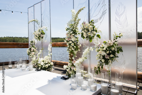 Side view of wedding ceremony with white transparent screens and fresh white flowers and candles