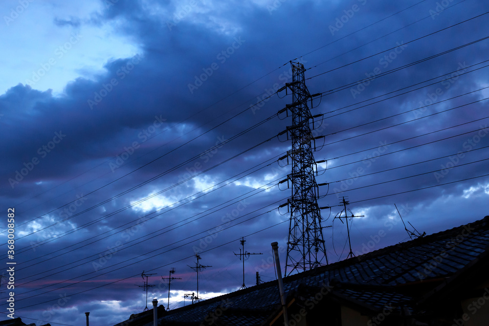 A scenic view of a pylons and houses in the shadows at night when the sun is about to set completely.