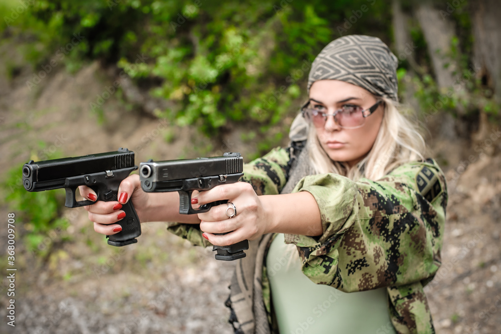 Attractive soldier woman practice shooting with two gun and gun point aim to attacker. Abstract close-up pistol wide angle pointing front view. Nature outdoor Attractive soldier woman practice shooting with two gun and gun point aim to attacker. Abstract close-up pistol wide angle pointing front view. Nature outdoor