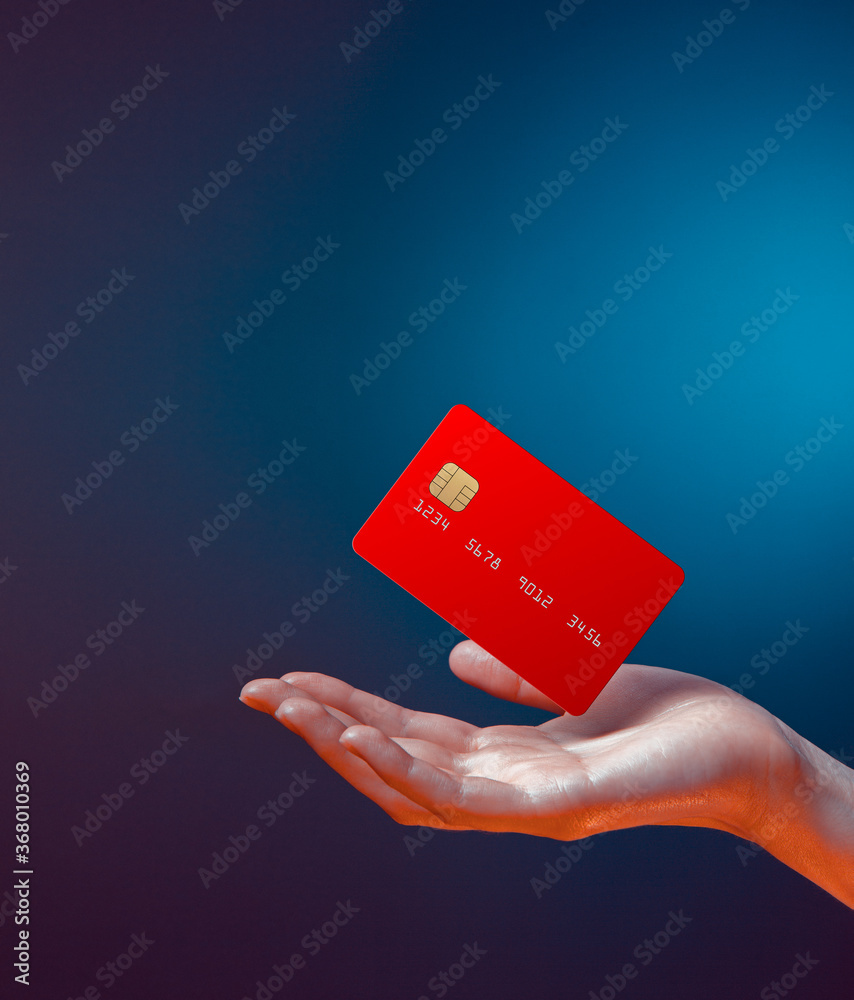 Close up female hand holds levitating template mockup Bank credit card with online service isolated on blue background - obrazy, fototapety, plakaty 