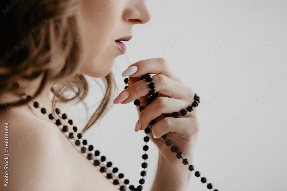 Attractive caucasian woman twirled a string of black  beads around her fingers