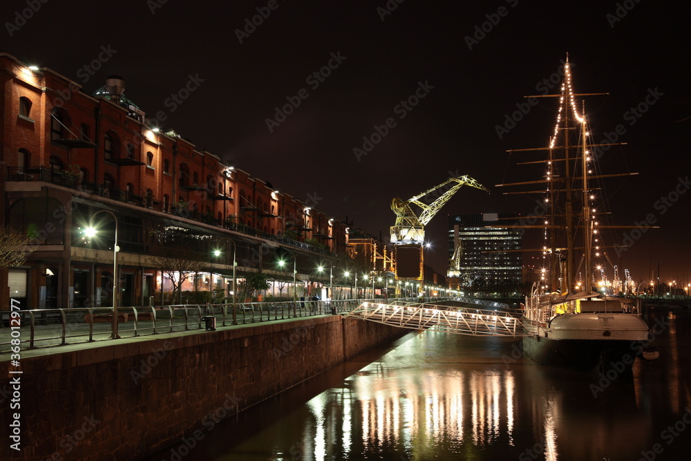 View of Puerto Madero Waterfront with crane and sailing ship at night in Buenos Aires, Argentina.