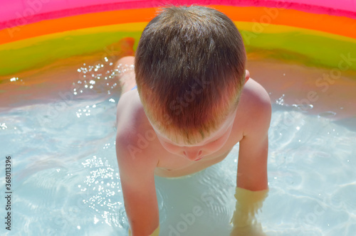 close-up - a five-year-old boy is actively resting - is engaged in physical education in the water of an inflatable pool, is wrung out