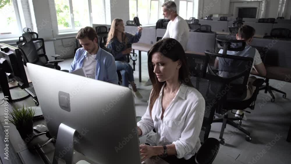 Business people office workers group using pc working talking in big modern coworking space, employees team women men sitting at desks with computers in modern enterprise interior at workplace