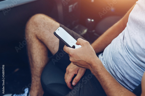 Photo of man hands touching phone in car. Lifestyle, travel, technology concept.