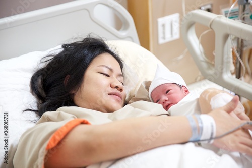 New born baby boy resting in mothers arms.
