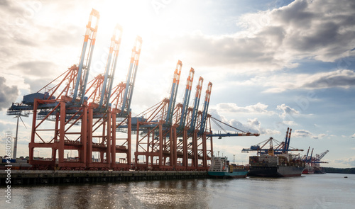 Sun beams through cranes at the harbor of Hamburg, Germany. photo