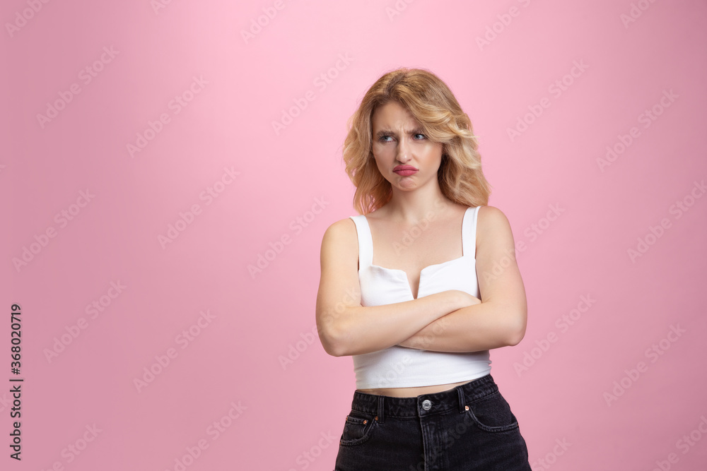 Offended, hands crossed. Caucasian young woman's portrait isolated on pink studio background. Beautiful blonde model. Concept of human emotions, facial expression, sales, ad, youth. Copyspace.