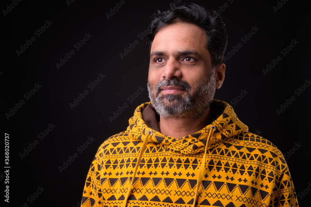 Fototapeta premium Portrait of mature bearded Indian man with curly hair wearing hoodie