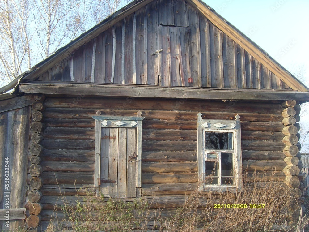 An old, abandoned wooden house with boarded-up Windows. A dying village