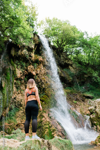 Young female nature explorer standing by the waterfall