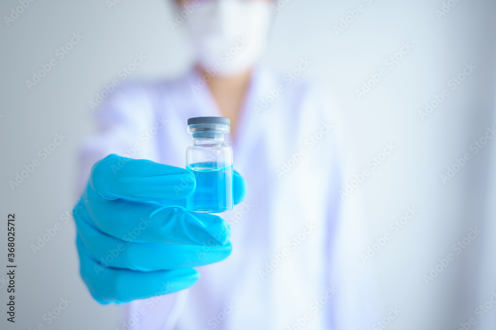 Female doctor or scientist in laboratory with stethoscope holding holds an injection syringe and COVID-19 or coronavirus vaccine. Healthcare And Medical concept. Female doctor or scientist in laboratory with stethoscope holding holds an injection syringe and COVID-19 or coronavirus vaccine. Healthcare And Medical concept.