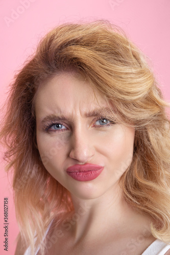 Doubts, pain. Caucasian young woman's close up portrait isolated on pink studio background. Beautiful blonde model. Concept of human emotions, facial expression, sales, ad, youth. Copyspace.