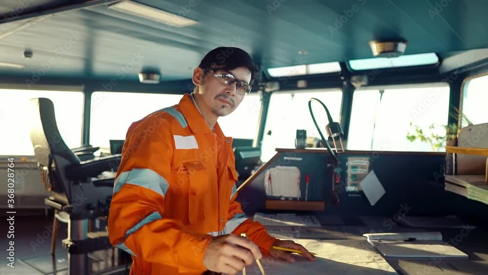 Filipino deck Officer on bridge of vessel or ship wearing coverall during navigaton watch at sea Filipino deck Officer on bridge of vessel or ship wearing coverall during navigaton watch at sea